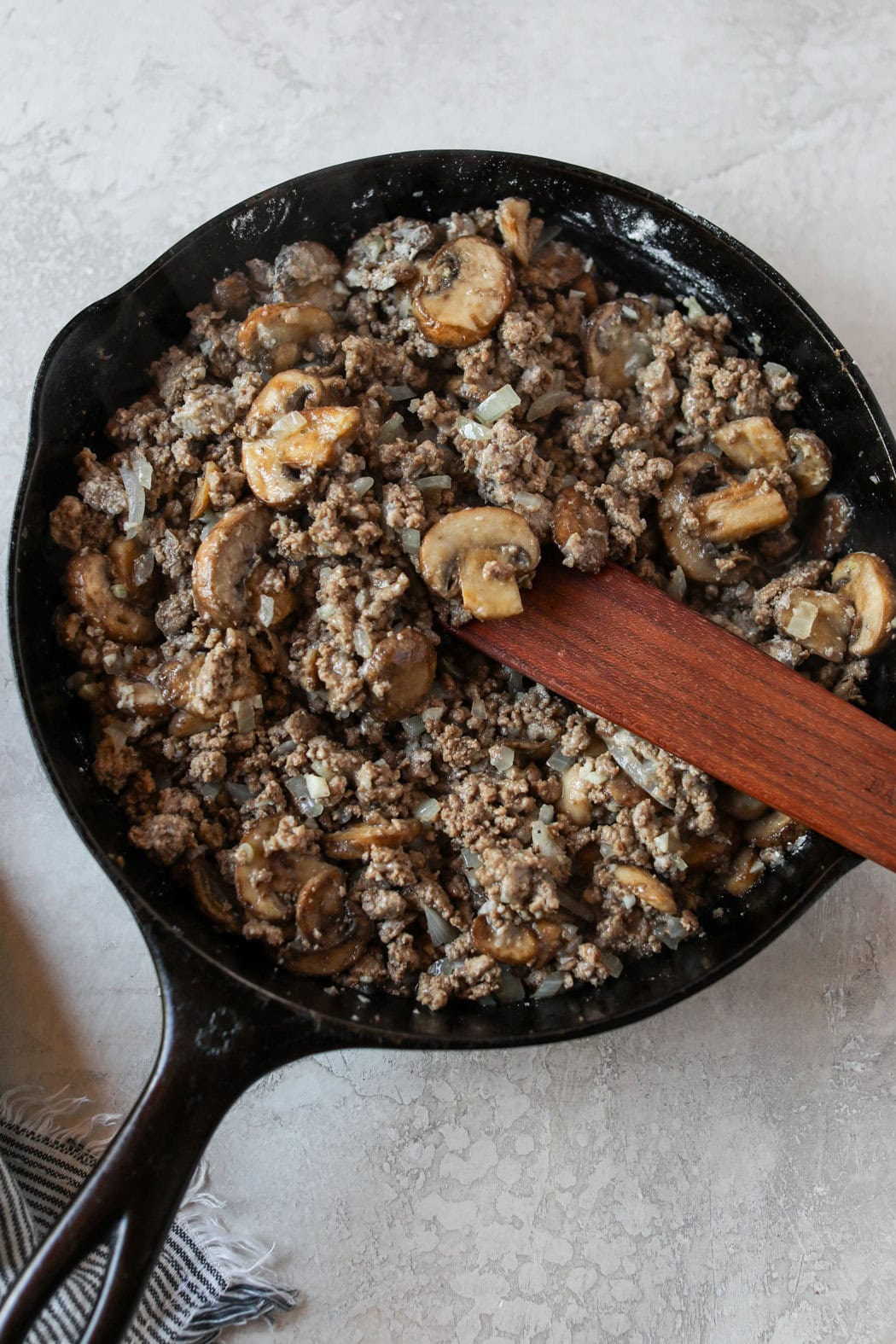 Overhead view of a pan of ground beef stroganoff cooking with mushroom pieces and ground beef. 