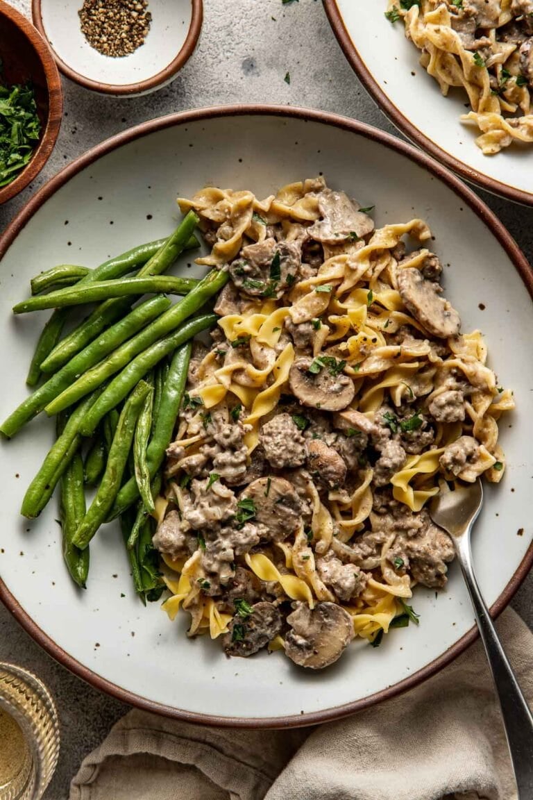 Close up view of a plate of Easy and Delicious Ground Beef Stroganoff with green beans on the side.