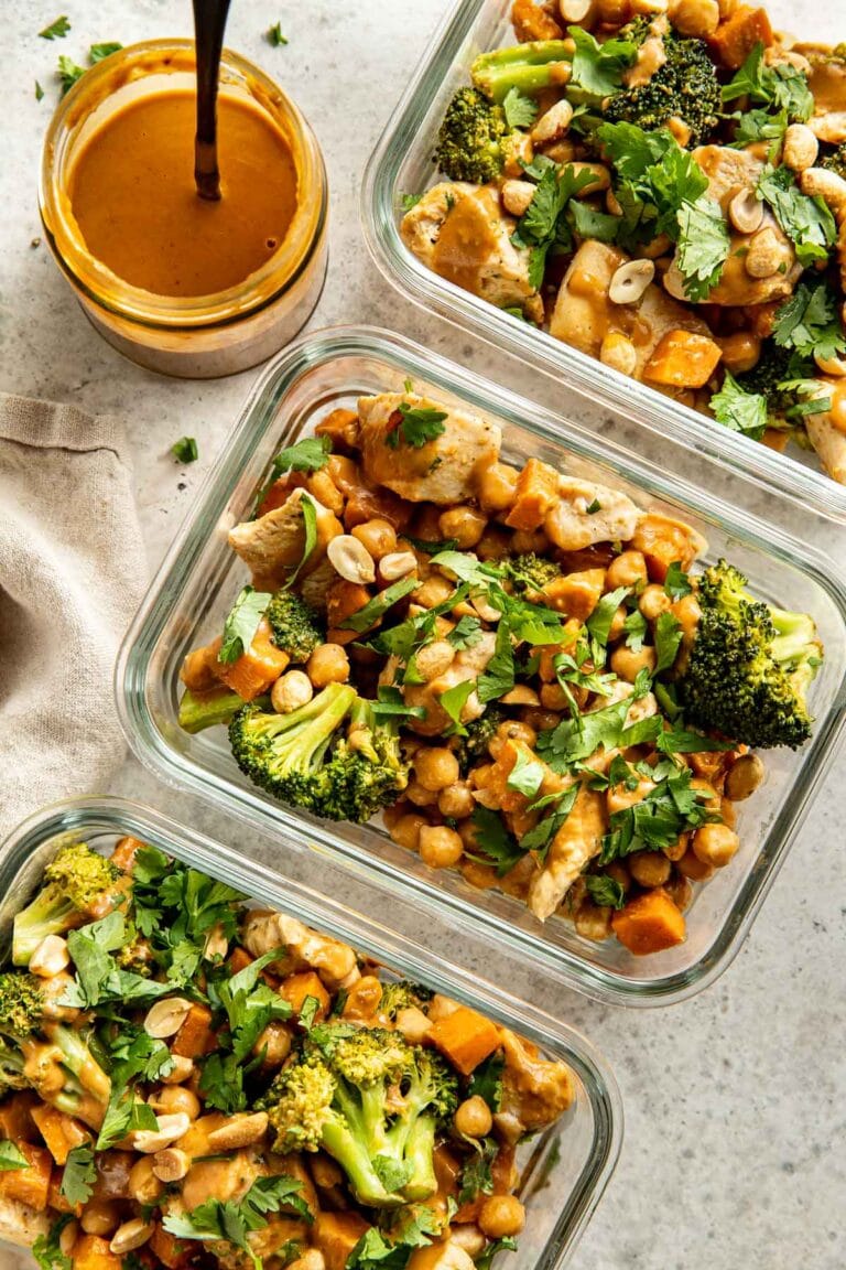 Overhead view of glass meal prep containers filled with Thai-Inspired Sweet Potato Peanut Bowl With Chicken