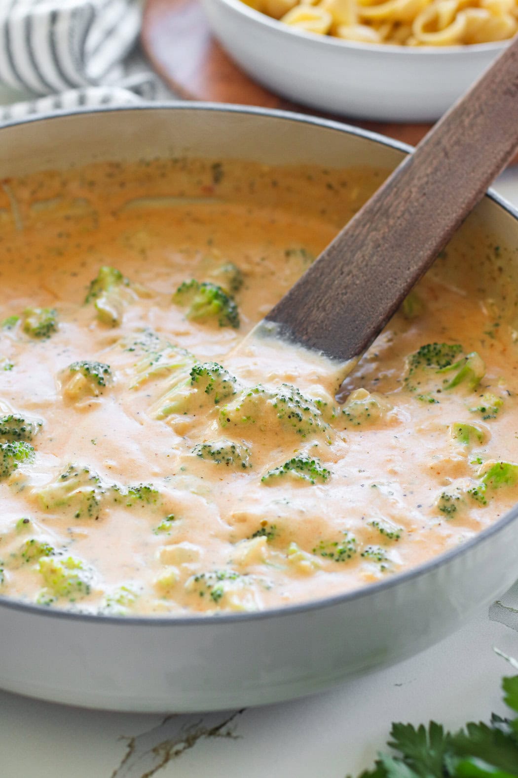 Close up view of ingredients for Homemade Hamburger Helper cooking in a skillet, being stirred with a wood utensil. 