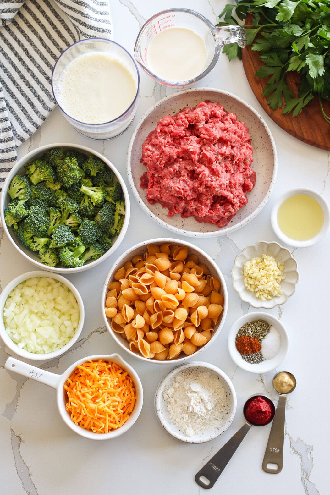 Overhead view of a variety of ingredients for Homemade Hamburger Helper in different sized bowls. 