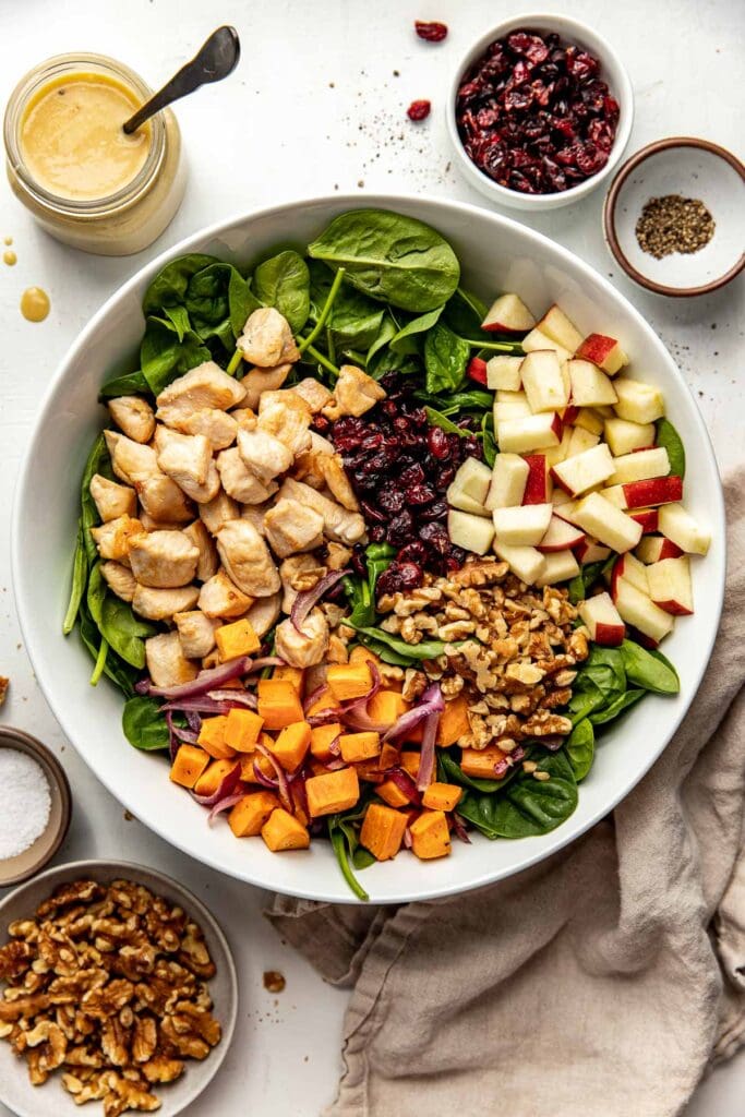 Overhead view of a bowl of ingredients for Harvest Chicken Salad with Maple Dijon Dressing ready for mixing and combining. 