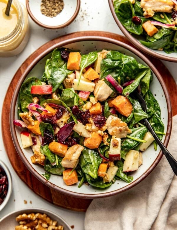 Plated harvest chicken salad over spinach with maple dijon dressing over top