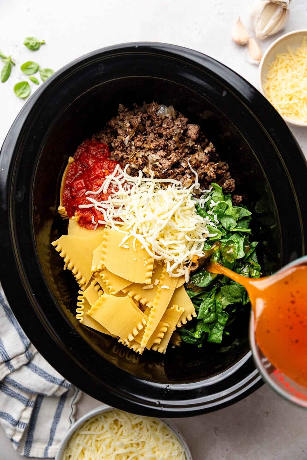 Overhead view of a slow cooker filled with ingredients for Crockpot Lasagna. 