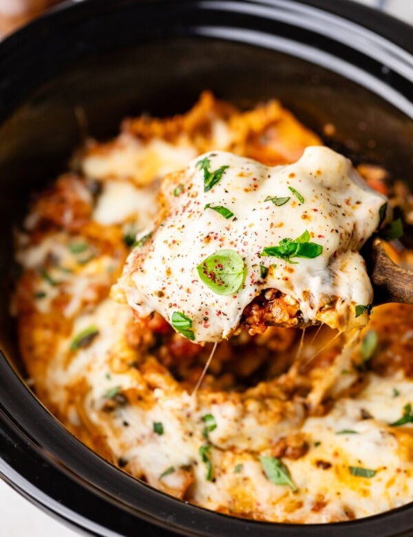 A black crockpot filled with cheesy lasagna