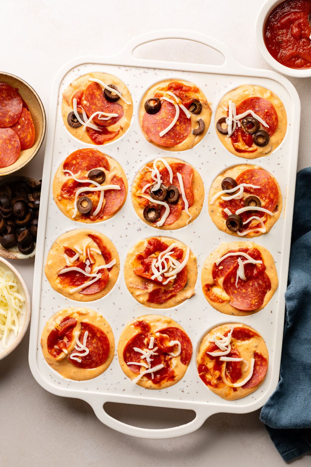 Overhead view of a muffin pan filled with Pepperoni Pizza Muffin batter ready for baking. 