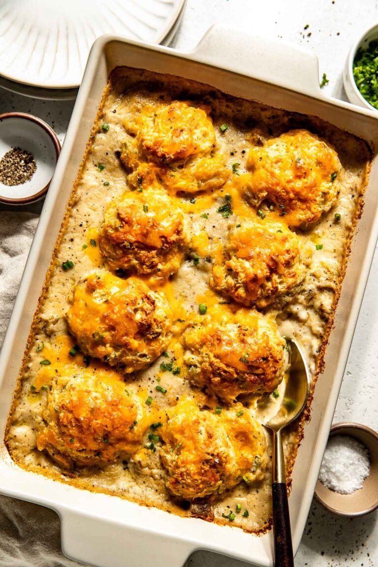 Overhead photo of baked casserole dish with gravy sausage topped with baked biscuits. 