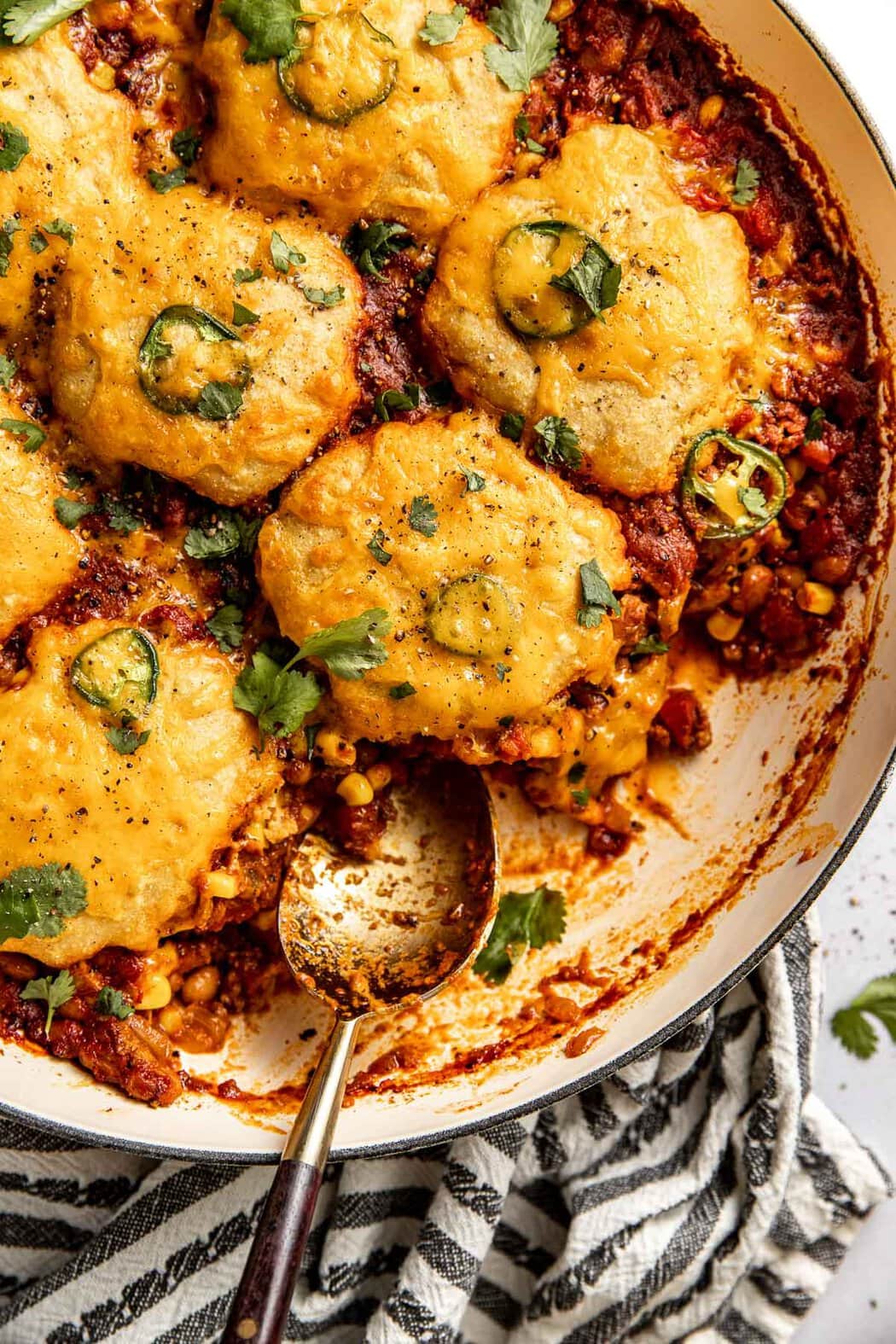 Close up view of a spoon sitting on a freshly baked pan of Chili Cornbread Casserole. 