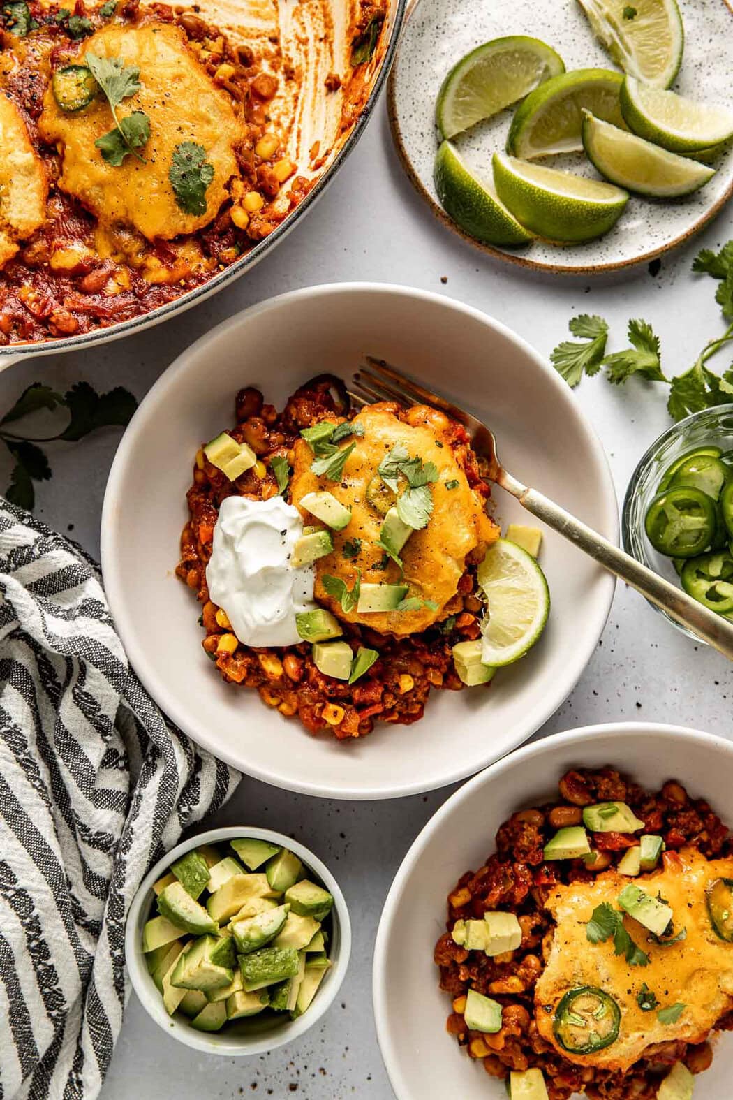 Overhead view of a plate of freshly baked Chili Cornbread Casserole on a plate topped with sour cream, avocado, and cilantro. 