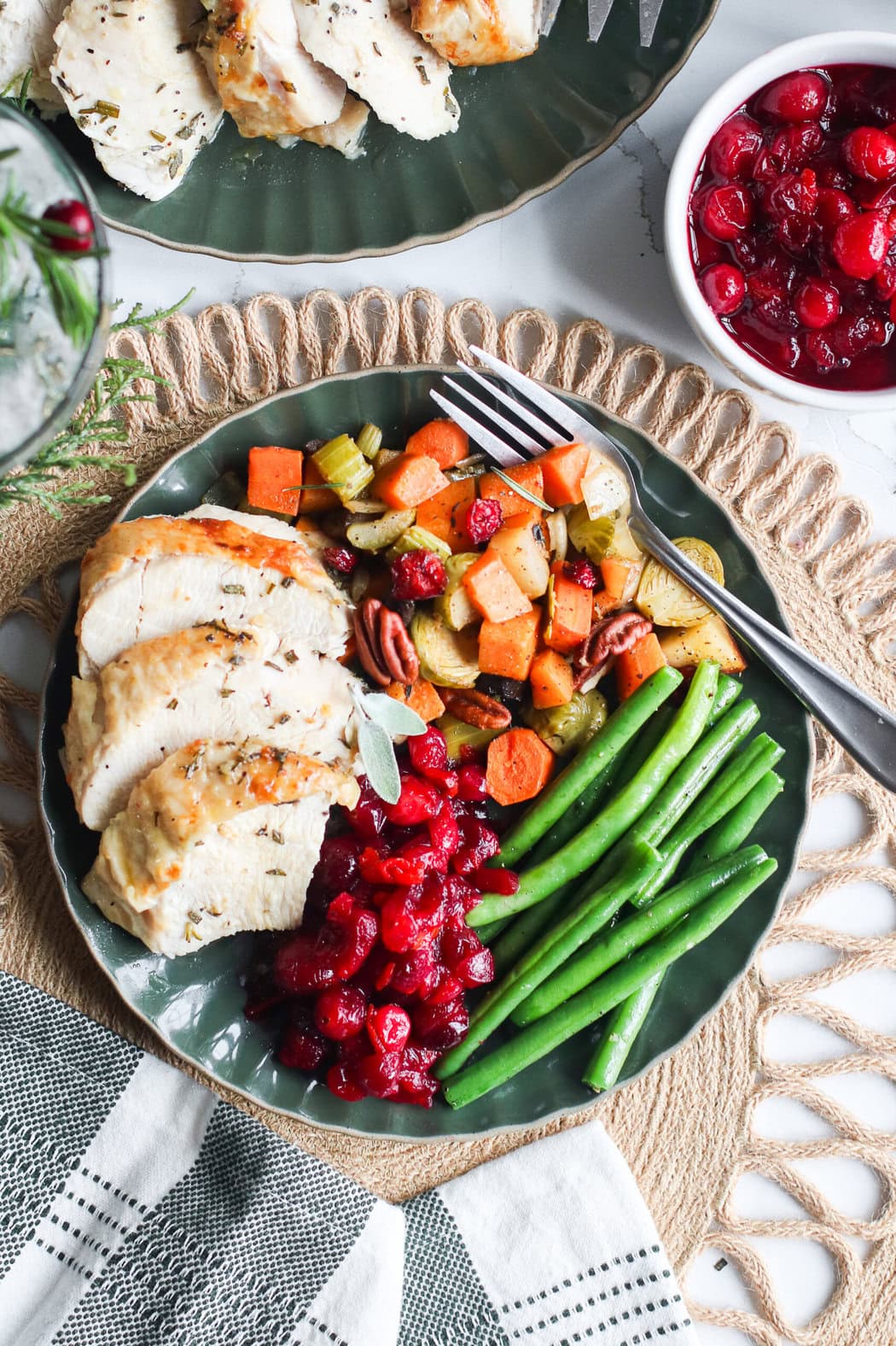 Overhead view of a plate filled with traditional thanksgiving foods including, roasted turkey, autumn vegetables, green beans and homemade cranberry sauce. 