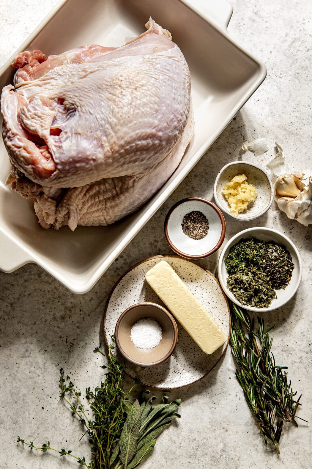 Overhead view of ingredients for The Best Simple Bone-In Roasted Turkey Breast in different sized bowls and dishes. 