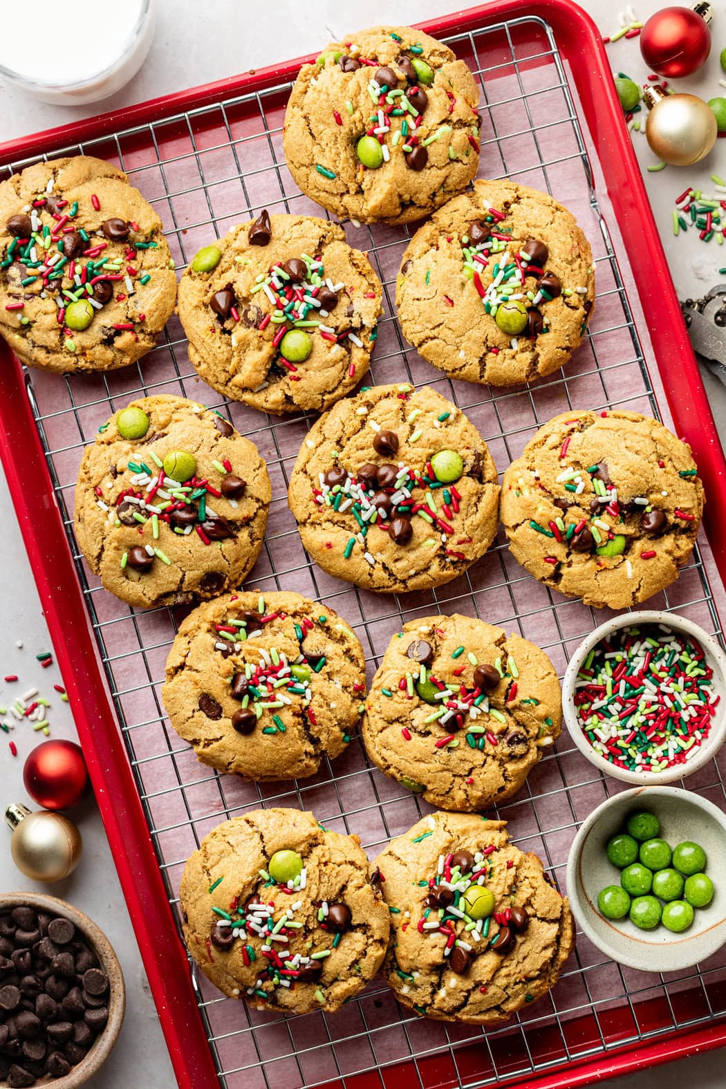 Overhead view of a cooling rack filled with Ana’s Christmas Cookies topped with festive sprinkles and candy chocolate pieces. 