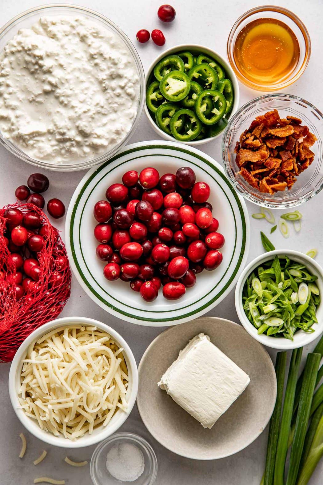 Overhead view of a variety of ingredients for Cranberry Jalapeño Dip (With Whipped Cottage Cheese) in different sized bowls. 