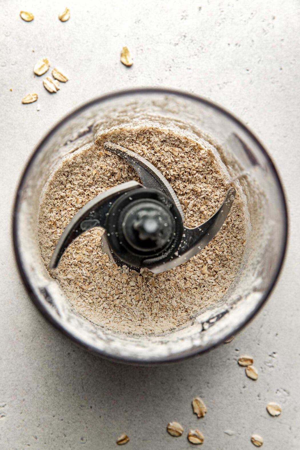 Overhead view of a food processor filled with old fashioned oats for pulsing. 