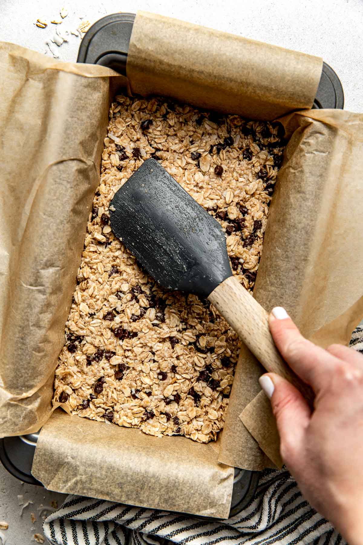 Overhead view of a pan of Copycat Heavenly Hunks dough being pressed into the pan with a spatula. 