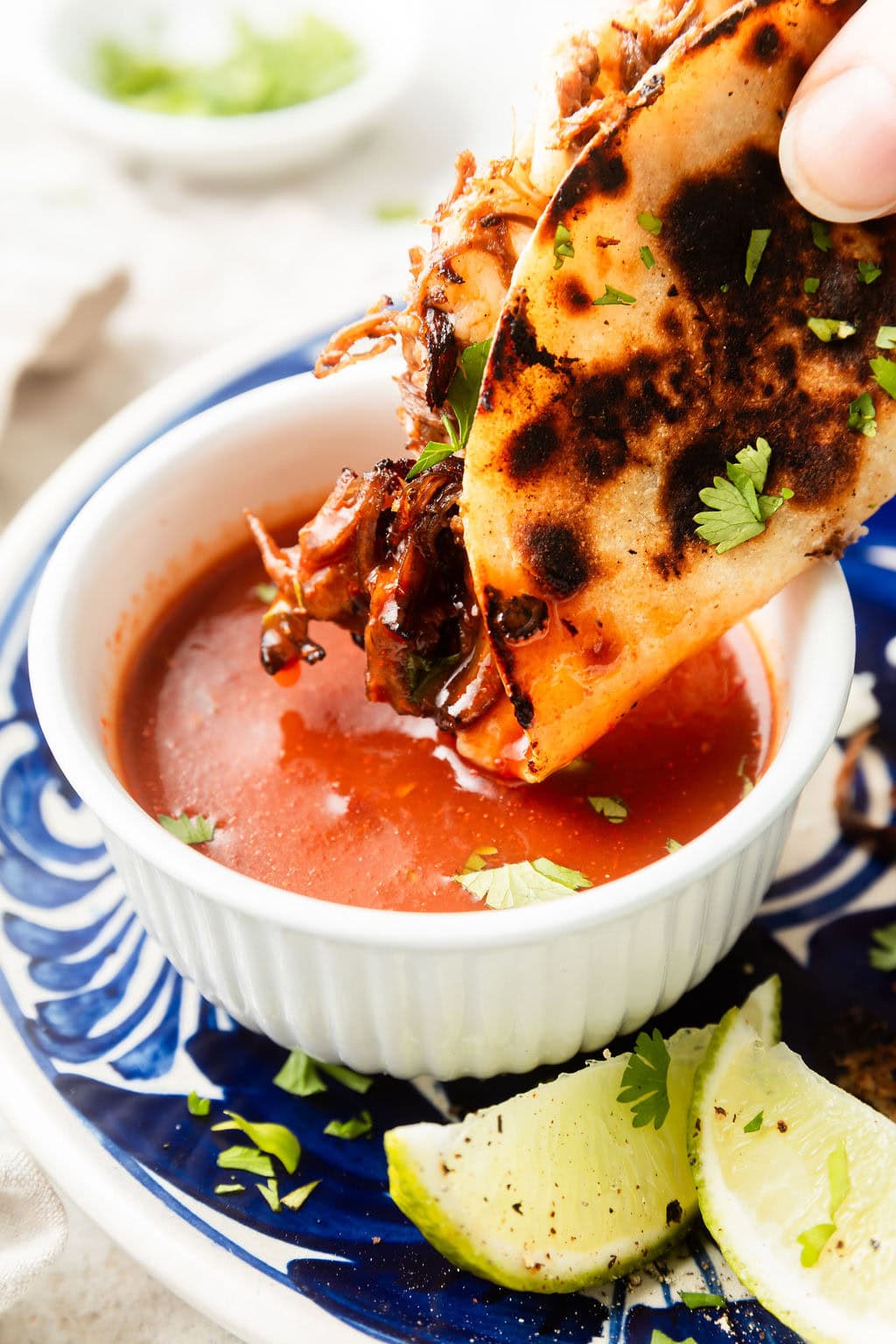 Close up view of a Crockpot Birria Tacos (Quesabirria) being dipped in sauce. 