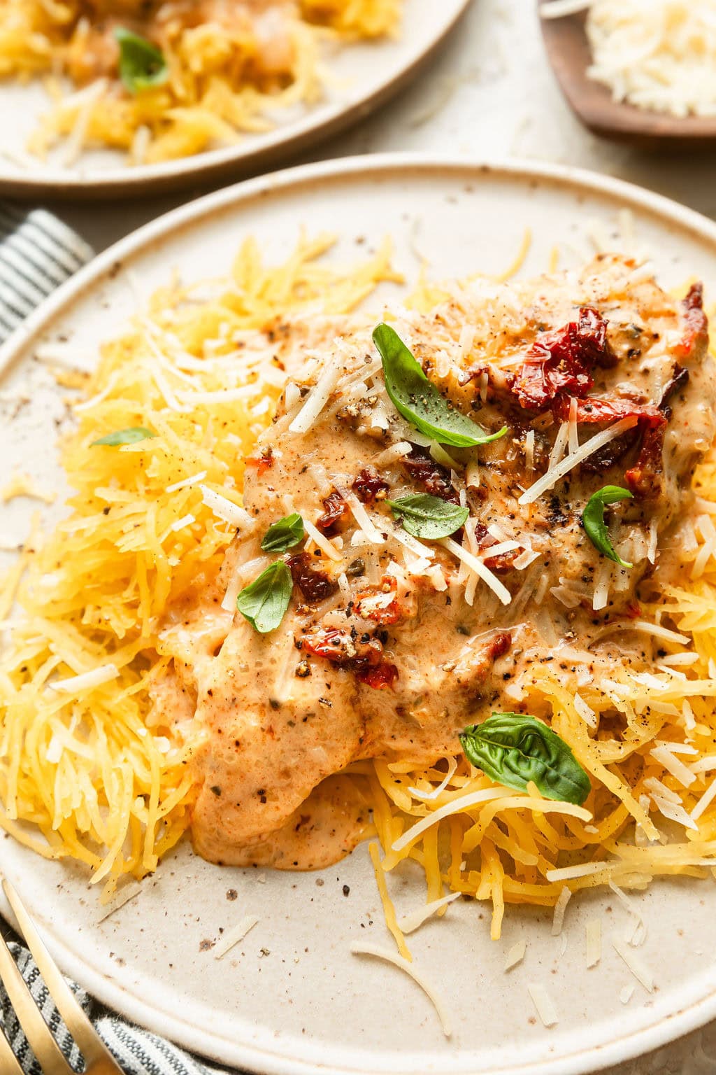 Close up view of a plate of Crockpot Marry Me Chicken topped with parmesan cheese and fresh basil. 