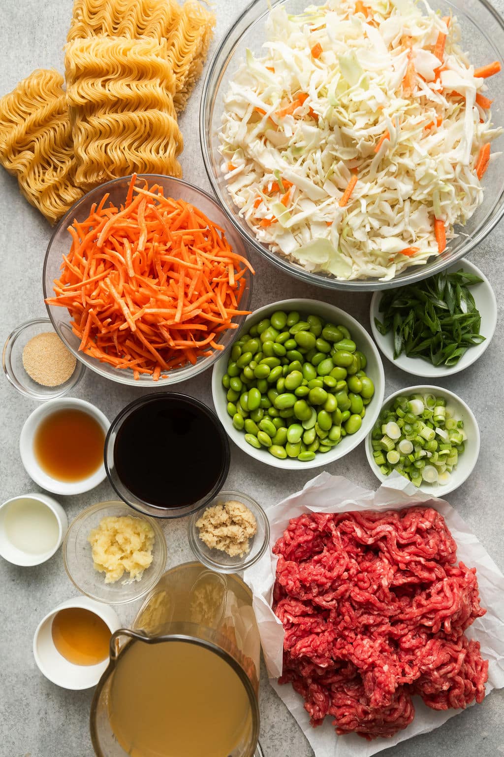 Variety of ingredients for Crockpot Beef Ramen in different sized bowls. 