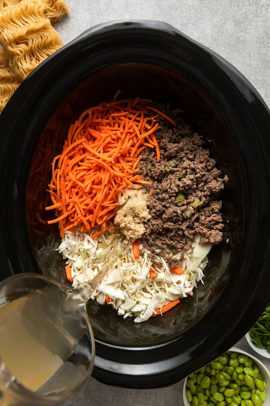 Overhead view of a crockpot filled with ingredients for Crockpot Beef Ramen. 