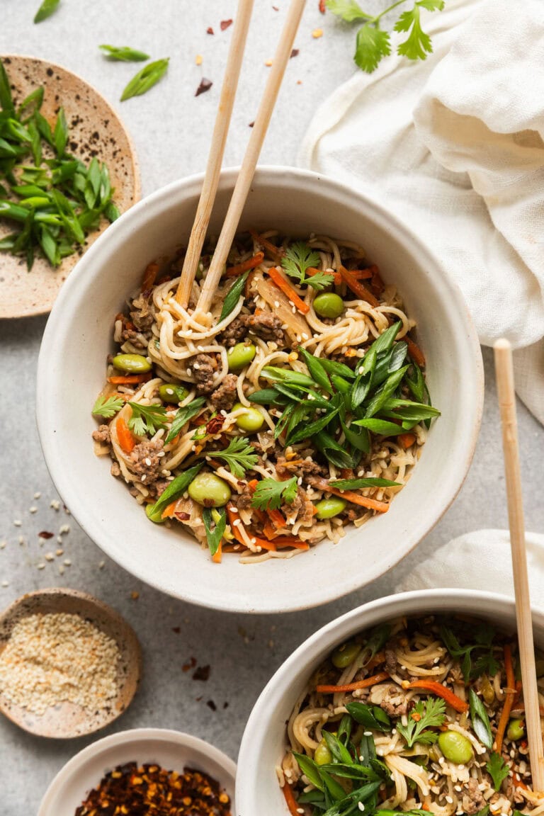 Overhead view of a bowl of crockpot beef ramen topped with edamame beans and green onions. 