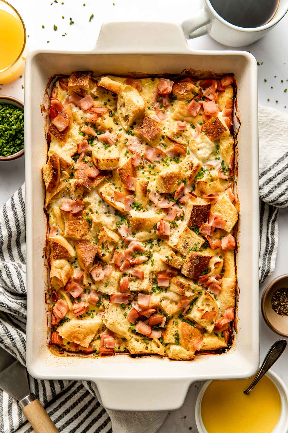 Overhead view of a freshly baked pan of Eggs Benedict Casserole topped with fresh chives. 