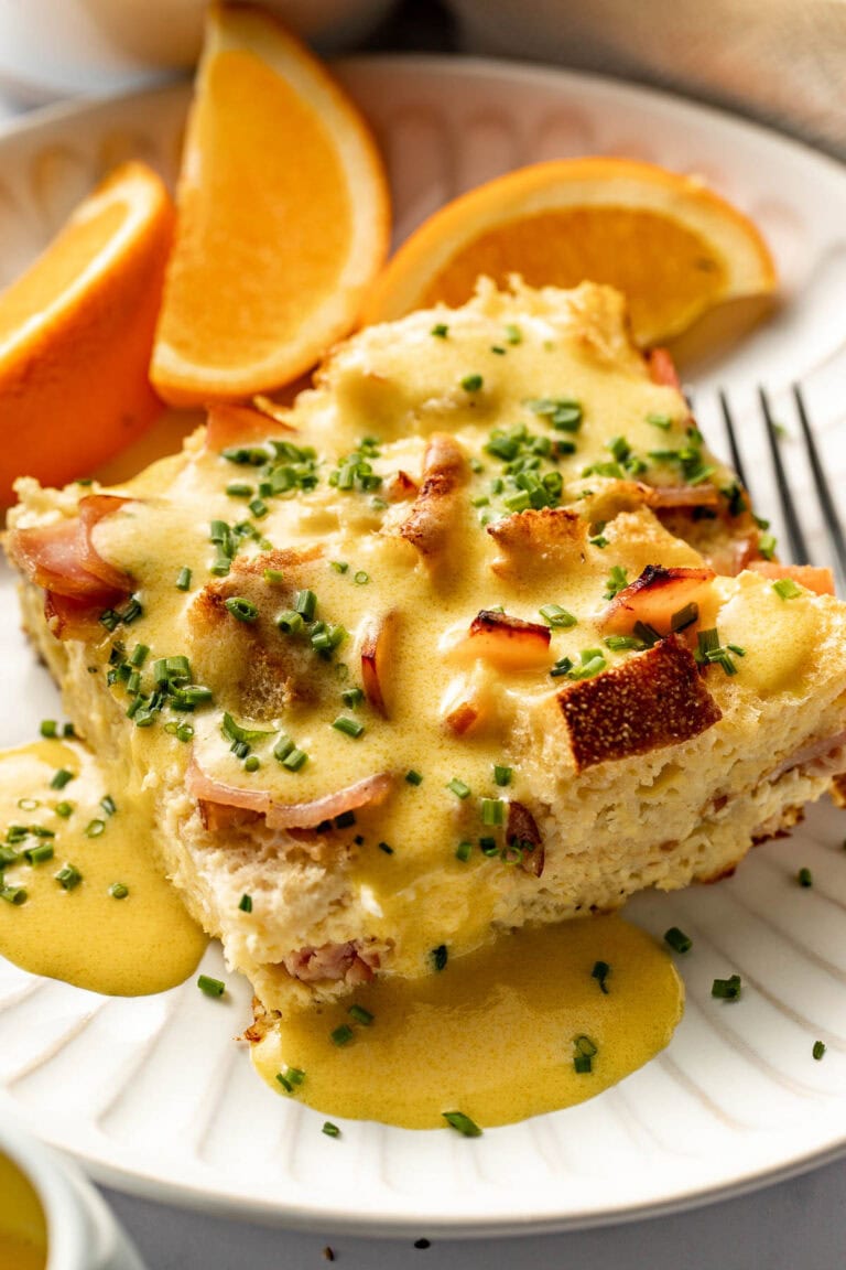 Overhead view of a plate of eggs benedict casserole with orange slices on the side.
