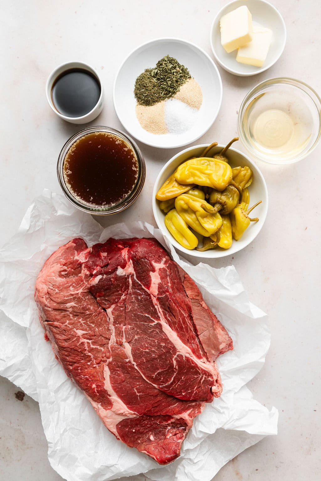 Overhead view of a variety of ingredients for Slow Cooker Mississippi Pot Roast in different sized bowls.