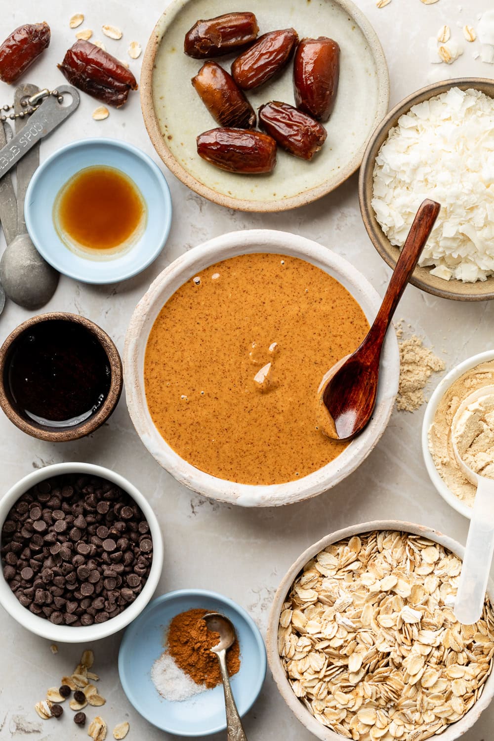 Overhead view of a variety of ingredients for Almond Butter Protein Balls in different sized bowls. 