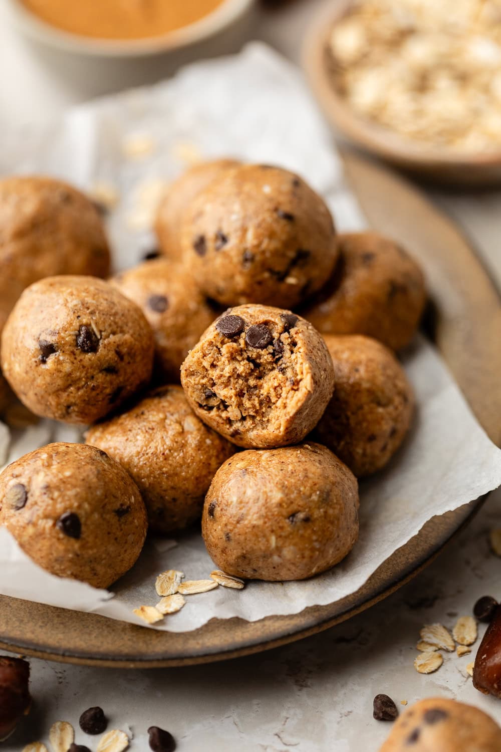 Close up view of a plate of Almond Butter Protein Balls with one having a bite out of it. 