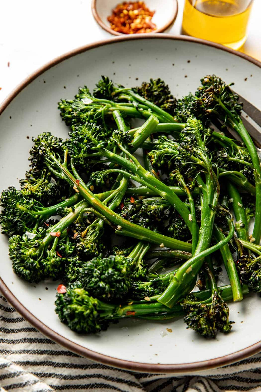 Close up view of a plate of Easy Sauteed Broccolini Recipe topped with sea salt. 