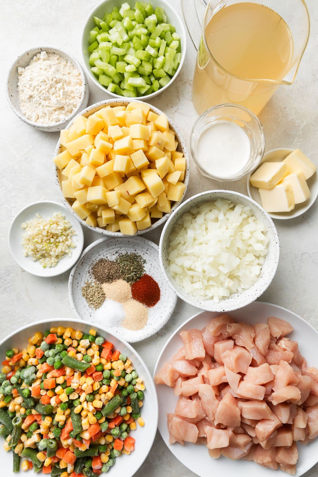 Overhead view of a variety of ingredients for Slow Cooker Chicken Pot Pie Soup in different sized bowls.