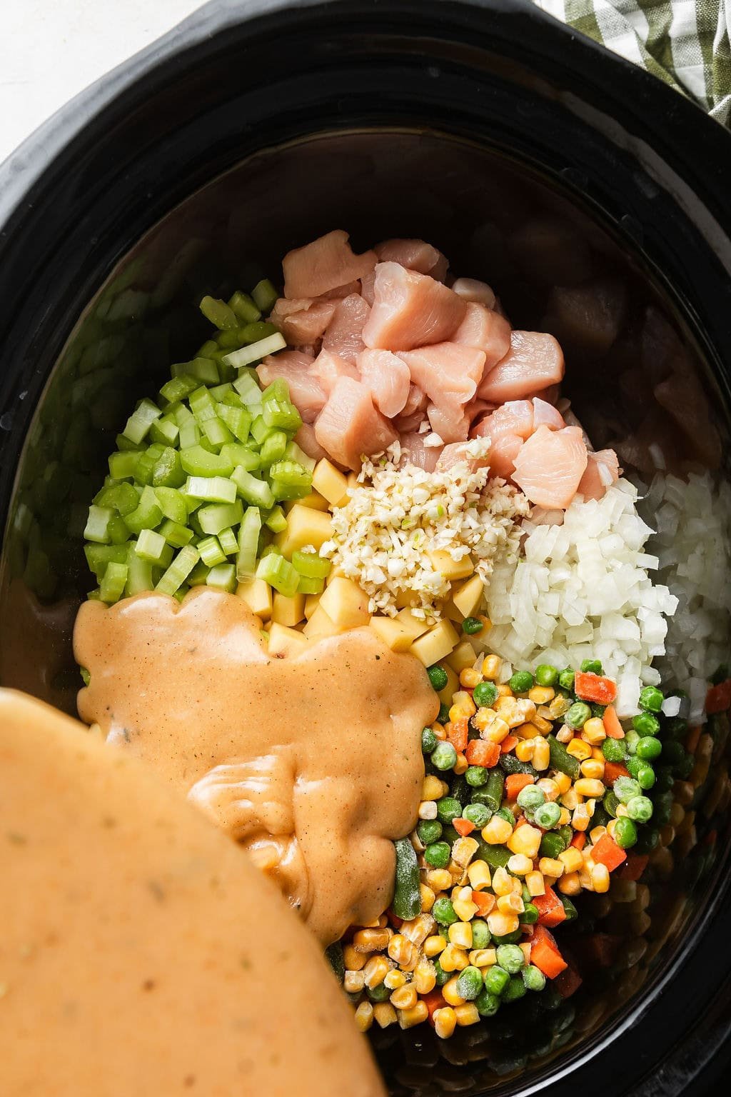 Overhead view of a slow cooker filled with ingredients for Slow Cooker Chicken Pot Pie Soup.