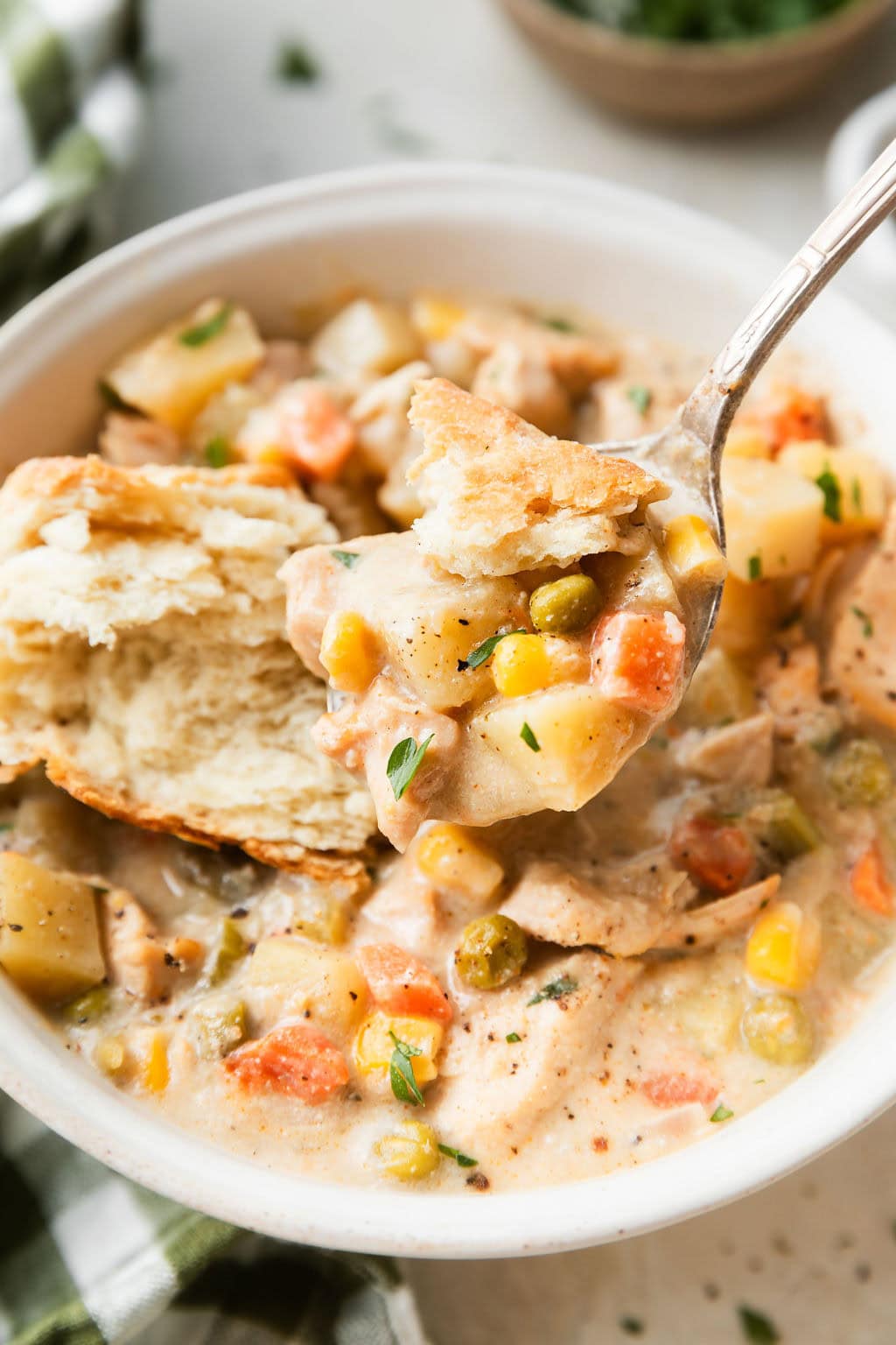 A spoon scooping a bite of Slow Cooker Chicken Pot Pie Soup from a bowl. 