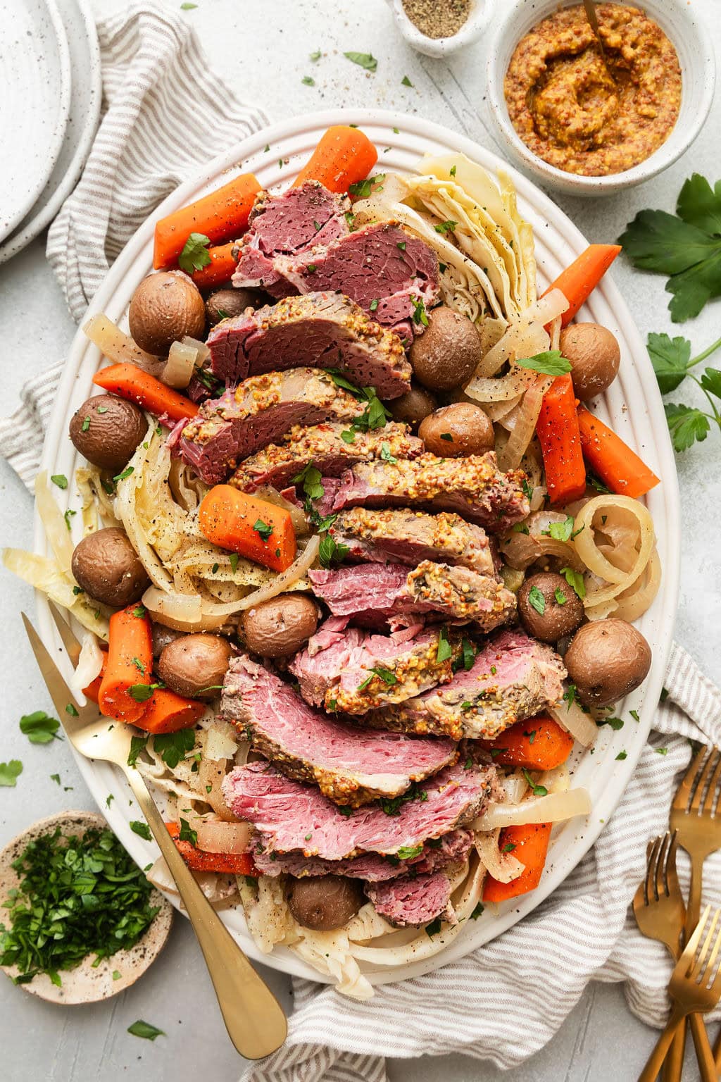 Overhead view of a platter of Crockpot Corned Beef and Cabbage with carrots and fresh herbs. 