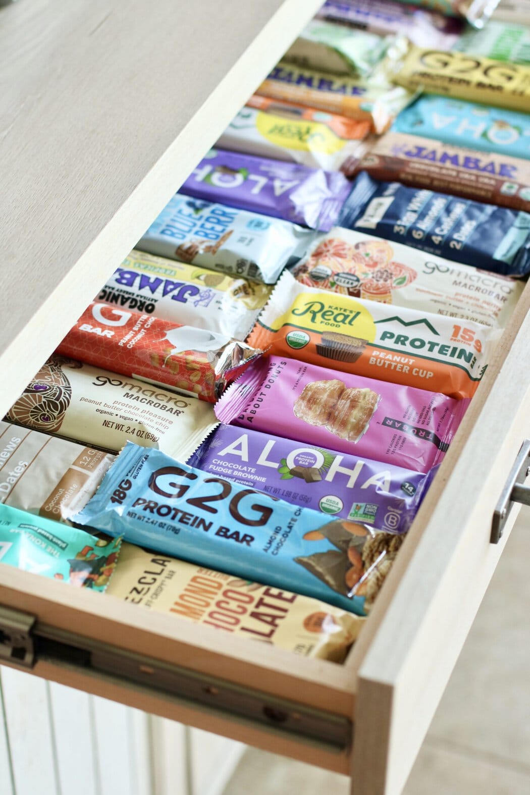 An open slide-out kitchen draw filled with rows of protein bars. 