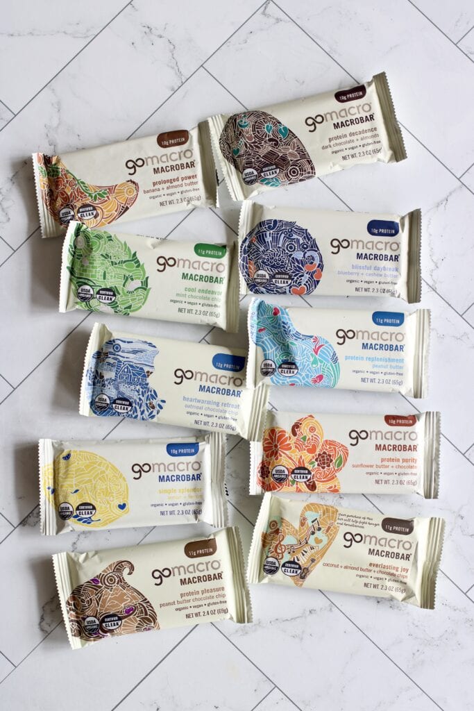Overhead view of a variety of go macro bars arranged on a white marble countertop.