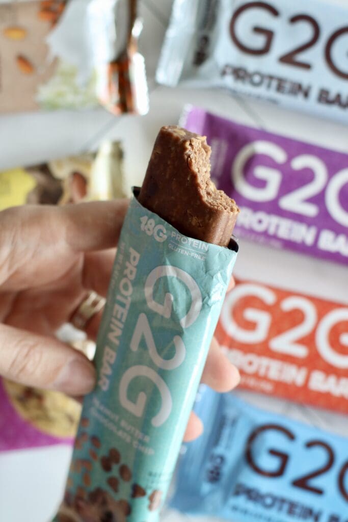 A hand holding an opened G2G bar with a bite out of the top to show the texture of the bar.