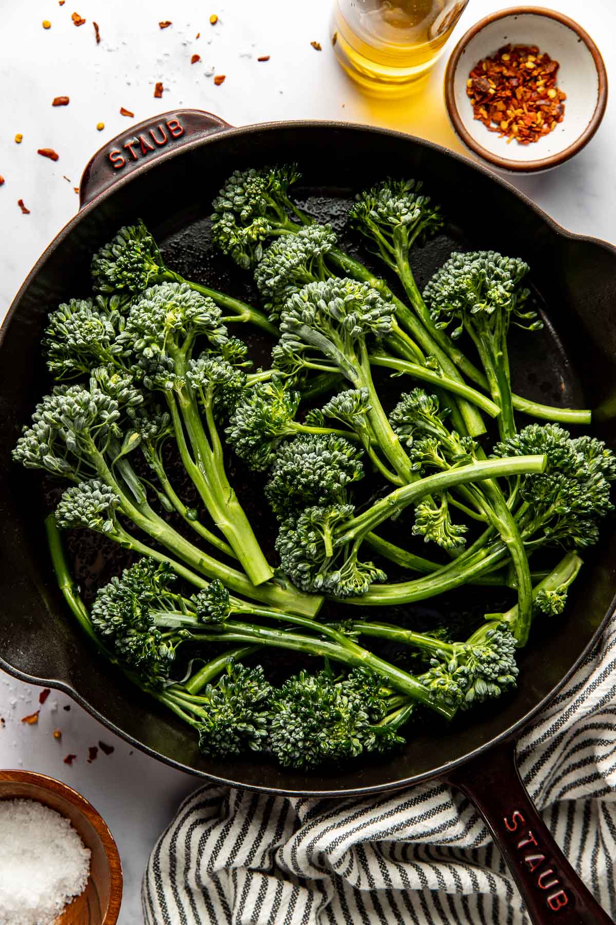 Overhead view of raw Broccolini in a cast iron skillet ready for cooking.