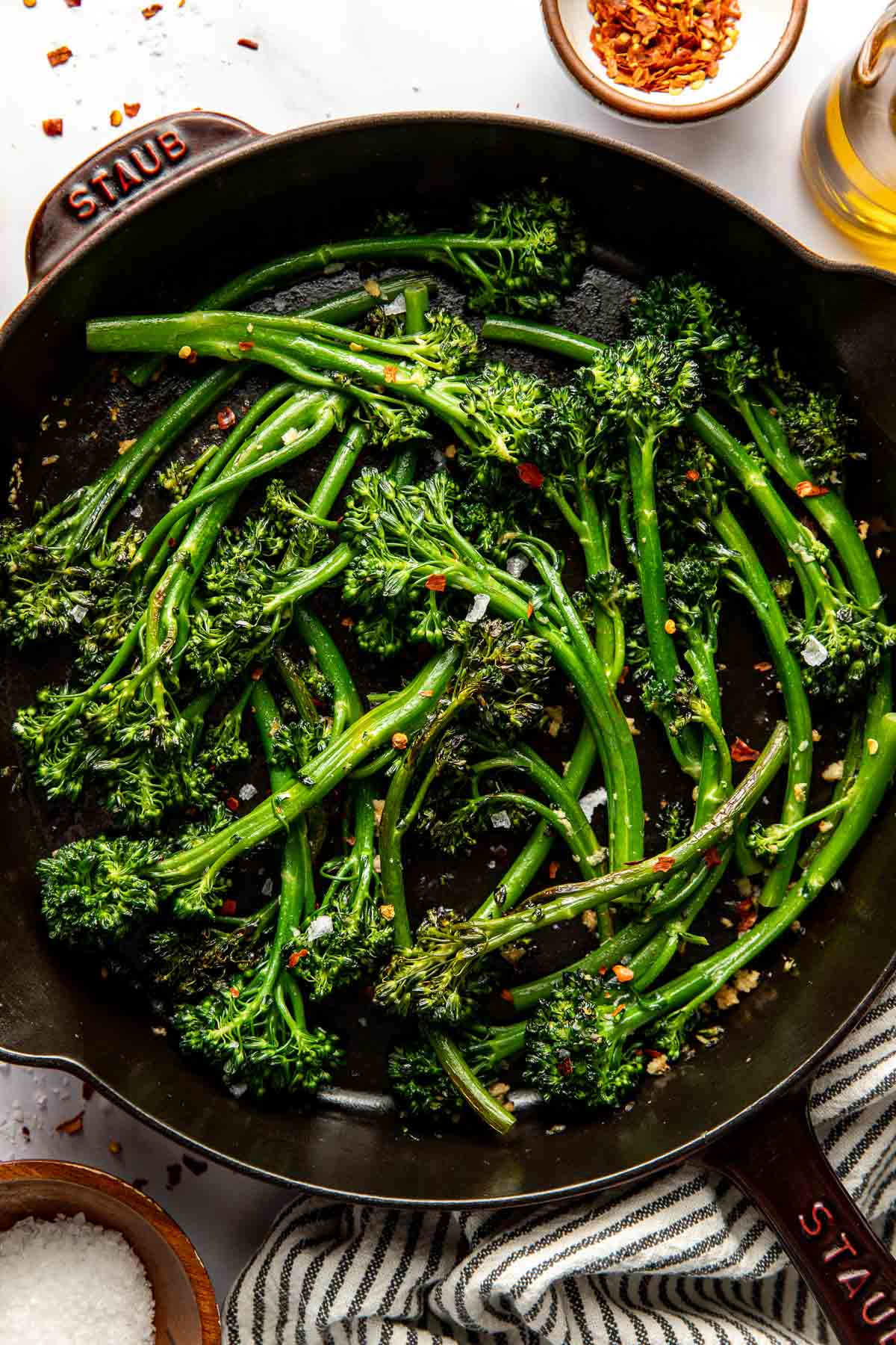 Overhead view of freshly Sauteed Broccolini topped with seasonings and flakey sea salt. 