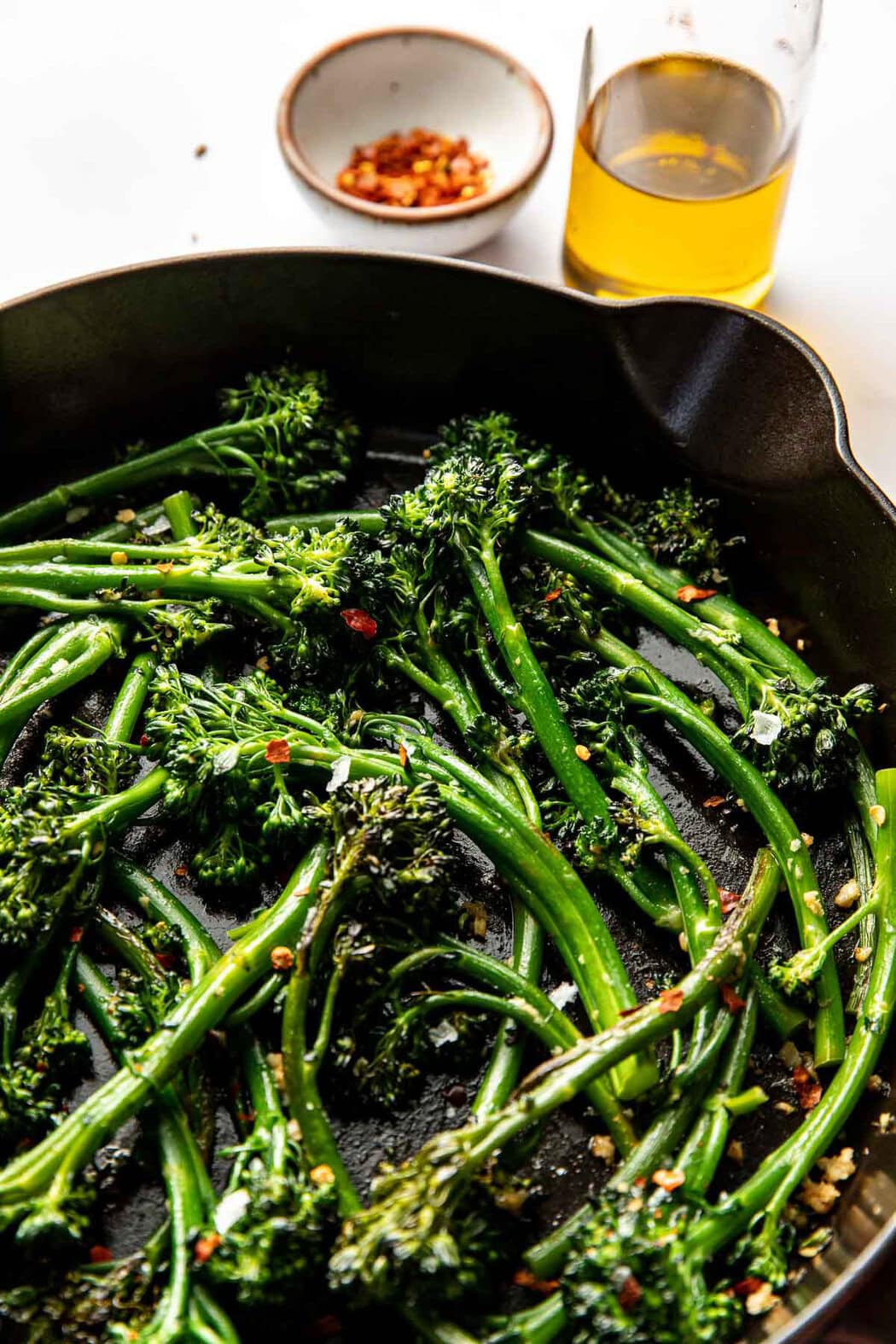 Close up view of freshly sauteed broccolini topped with seasonings and flakey sea salt. 