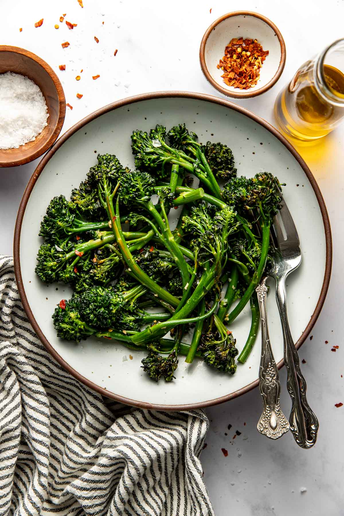 Sautéed broccolini on a plate, two forks on the side.