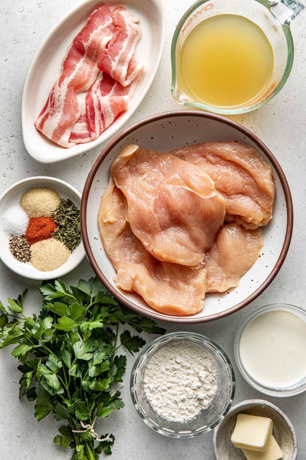 Overhead view of a variety of ingredients for Smothered Chicken in different sized bowls. 