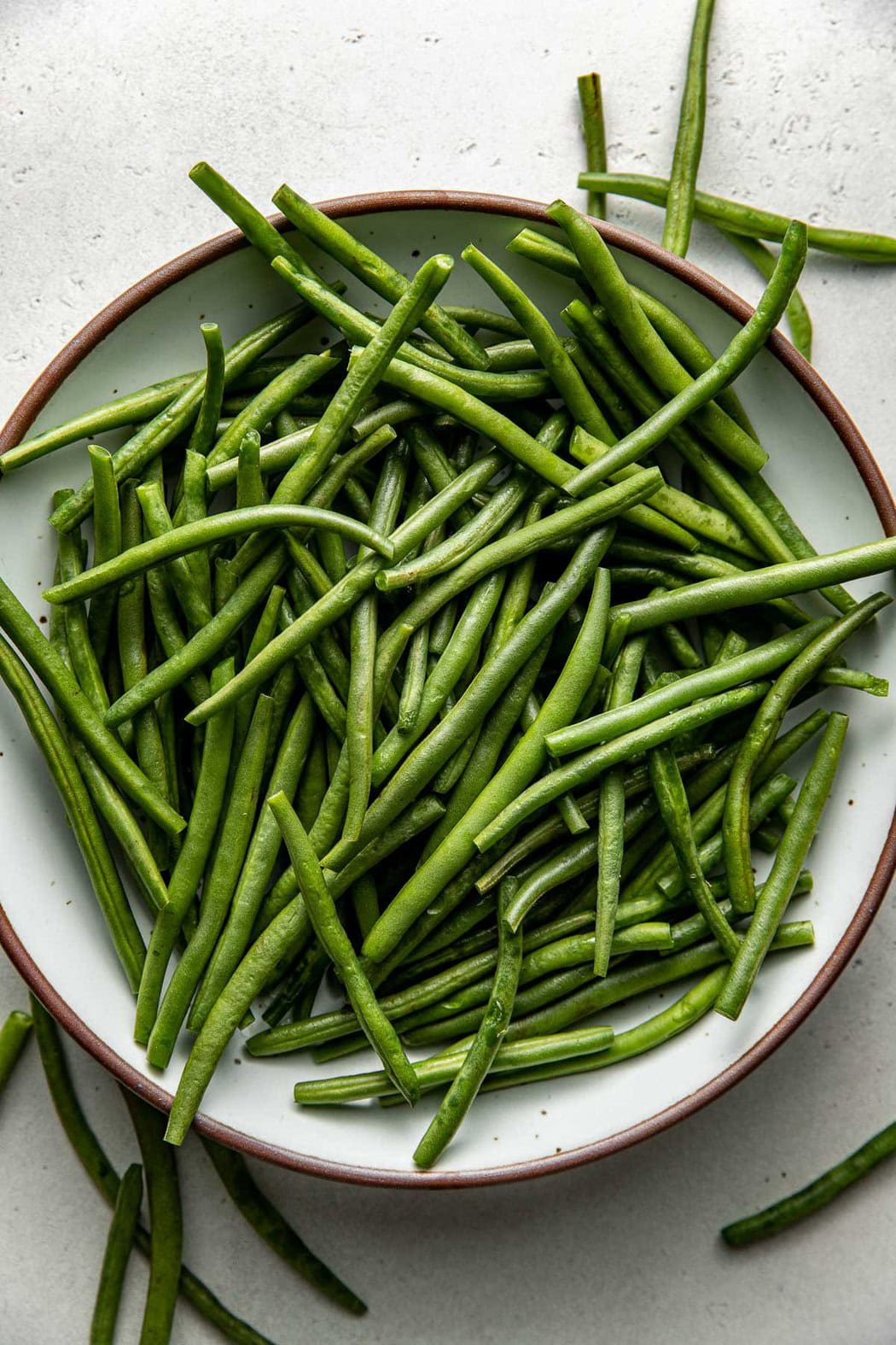 Overhead view of a plate of raw fresh green beans. 