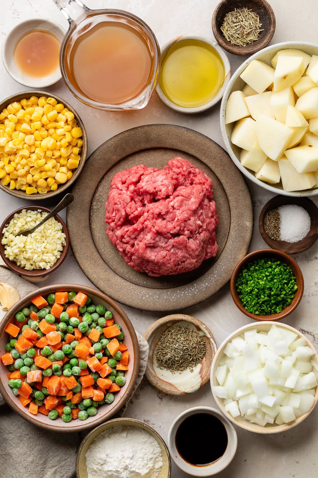 Overhead view of a variety of ingredients for Cottage Pie With Garlic Mashed Potatoes in different sized bowls. 