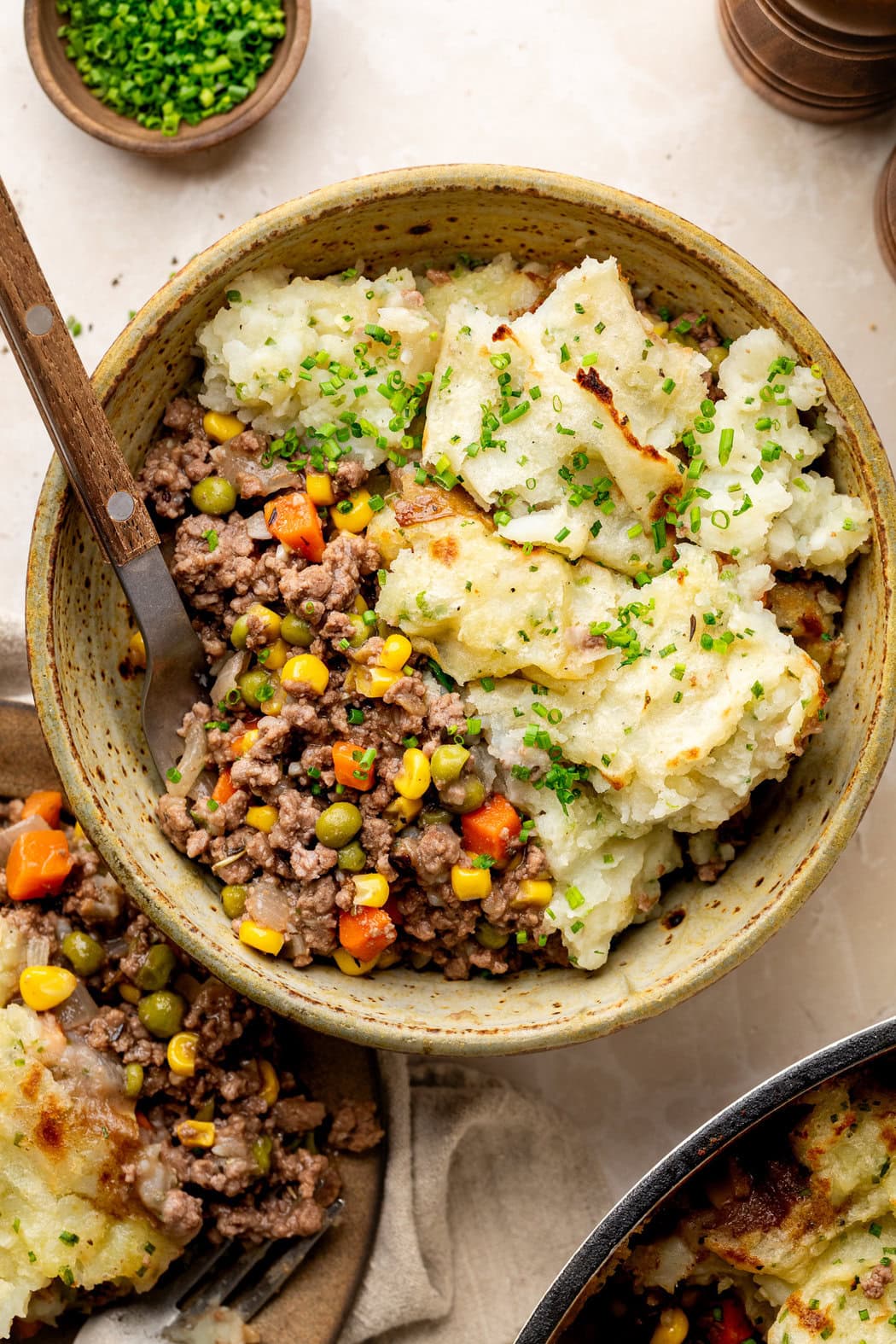 Overhead view of a bowl of Cottage Pie with Garlic Mashed Potatoes topped with fresh chives. 