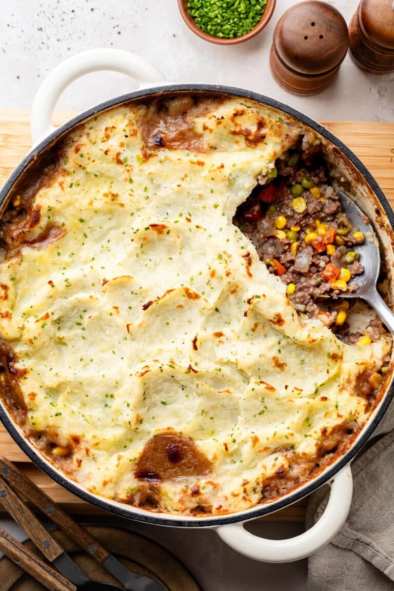 Overhead view of a skillet filled with cottage pie topped with creamy garlic mashed potatoes.