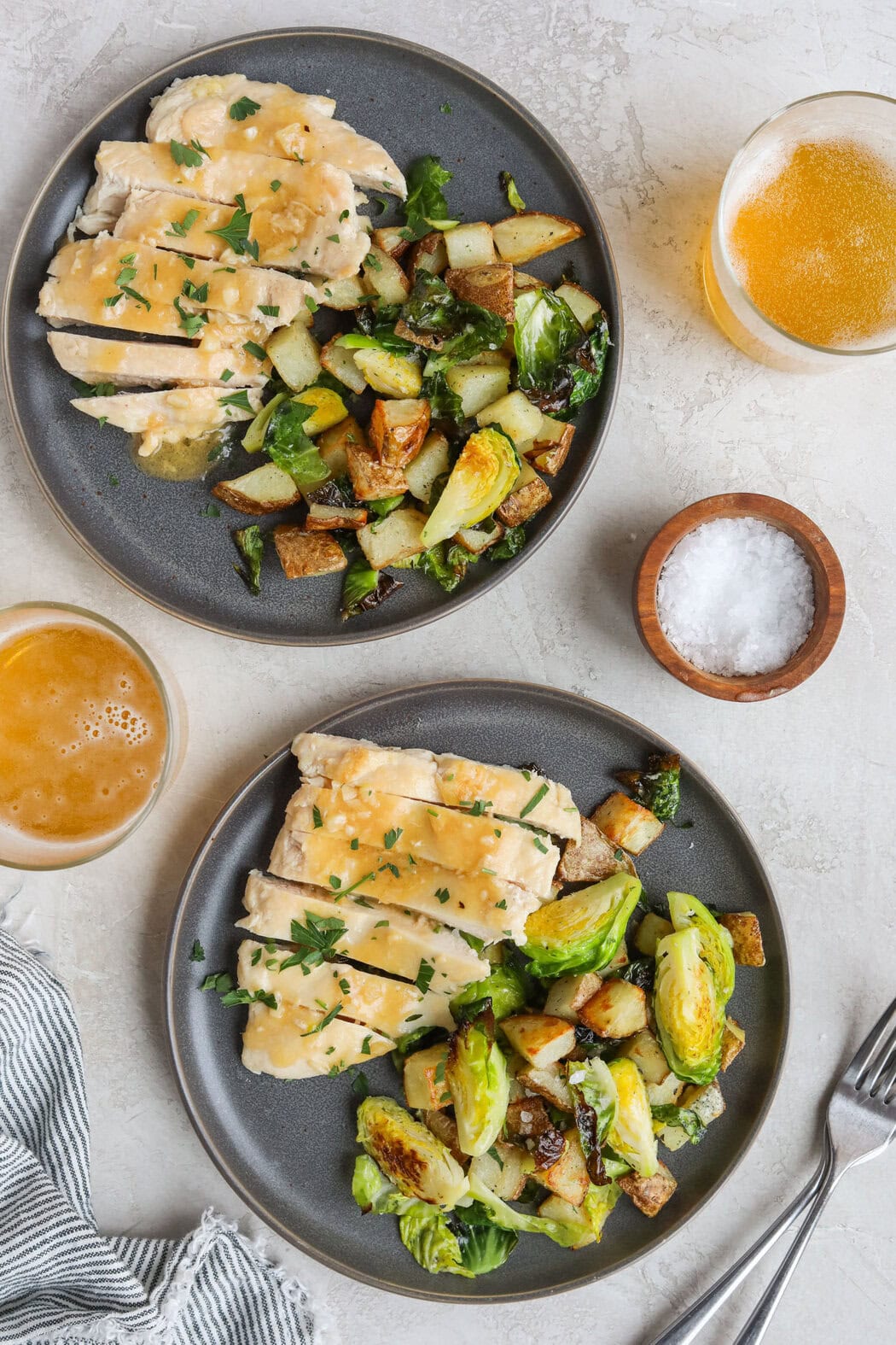 Overhead view of two freshly prepared Marley Spoon meals on blue plates including sliced chicken and roasted veggies. 