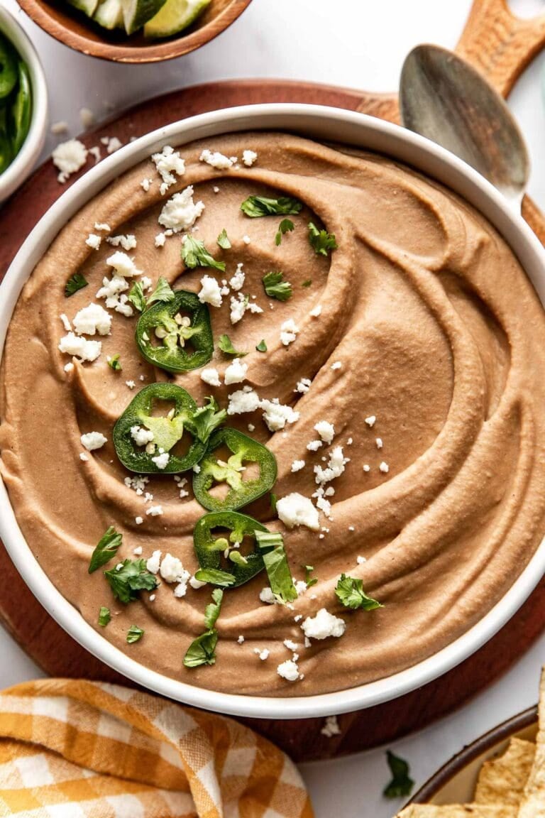 Overhead view of a bowl of homemade refried beans topped with jalapenos. 