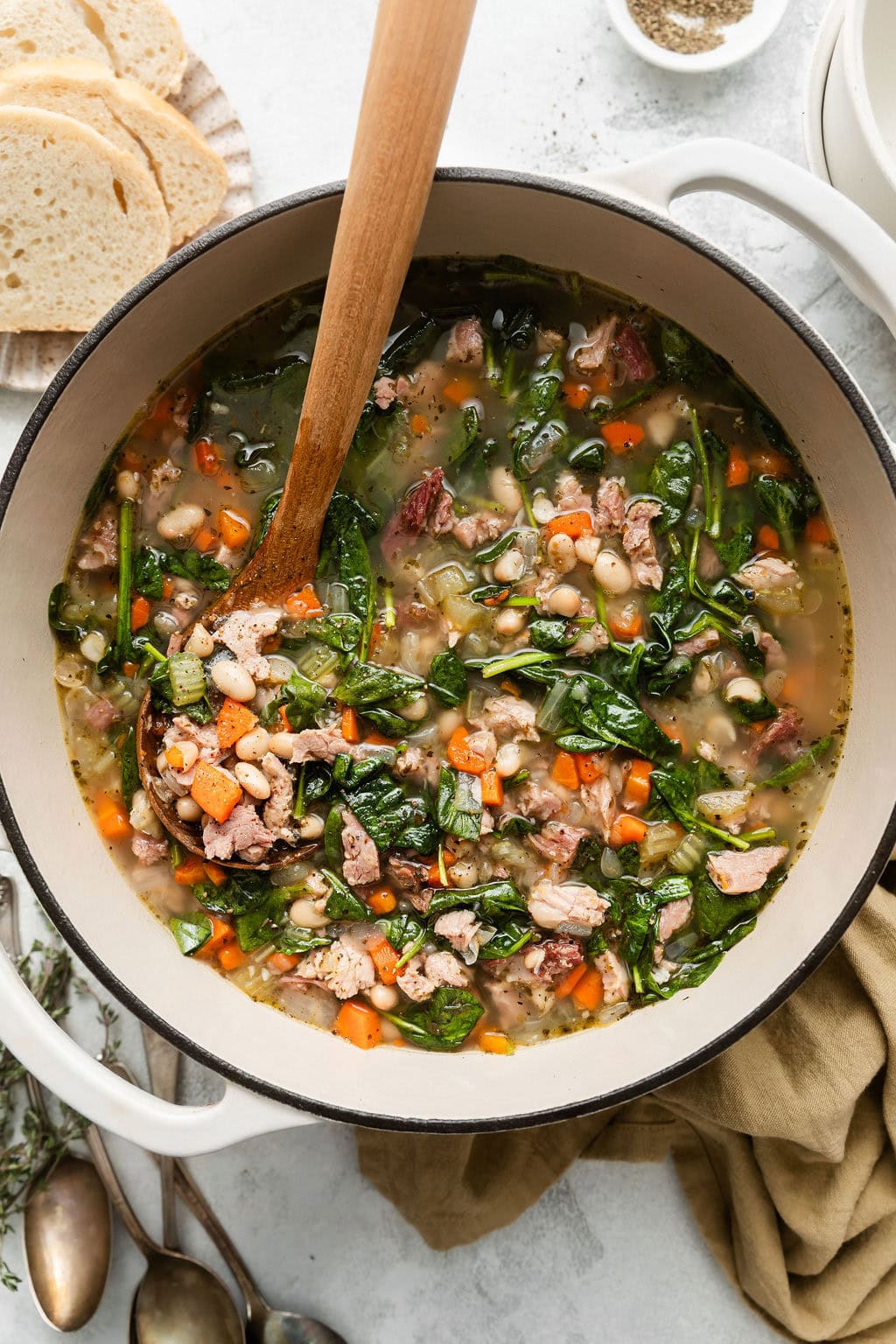 Close up view of a Dutch oven filled with Ham and Bean Soup topped with black pepper