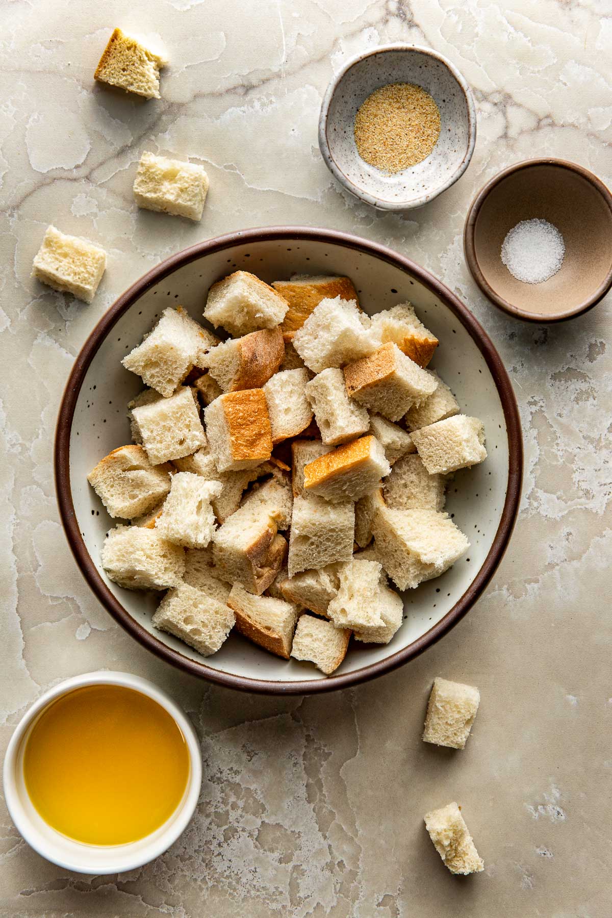 Overhead view of a variety of ingredients for Homemade Croutons in different sized bowls. 